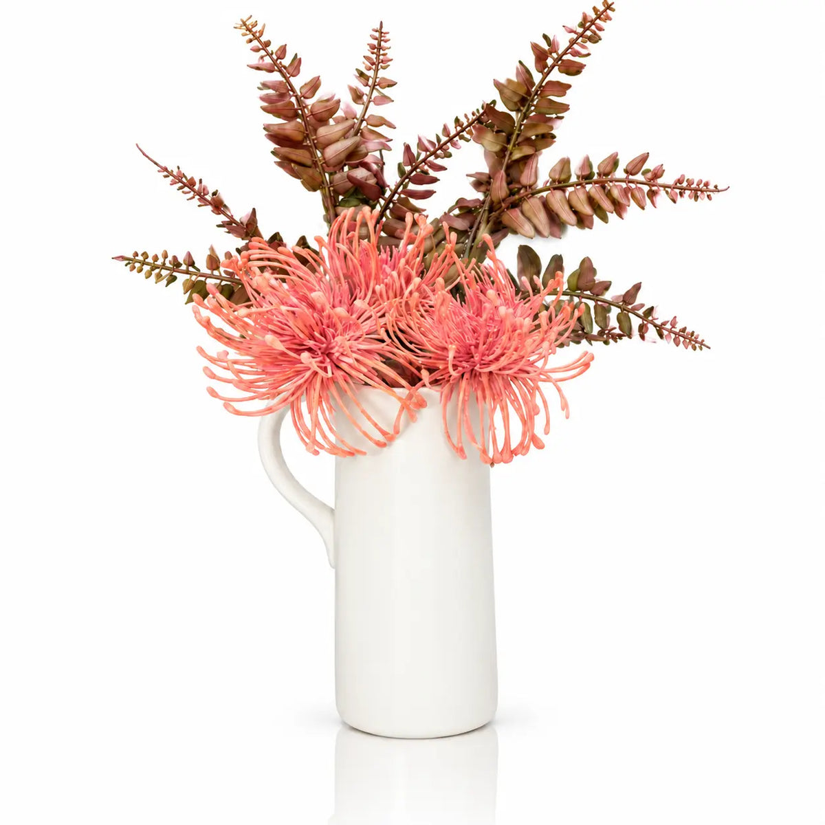 Pink faux floral white pitcher vase from Waterdale Collection, ceramic pitcher with coral pincushion blooms and burgundy fern