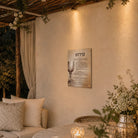 Painted by Batya Kiddush vinyl sukkah decoration with watercolor wine goblet artwork, hung on a sukkah wall beside a linen sofa and candlelit table