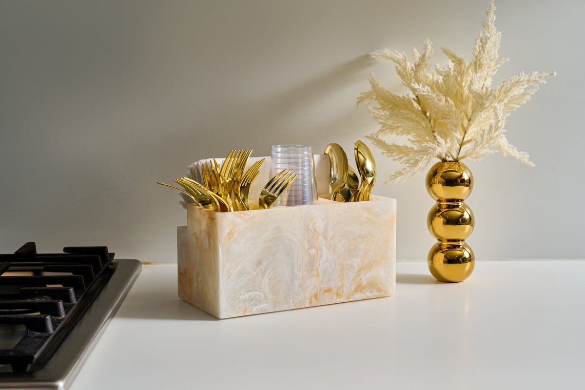 Elegant marble-look utensil holder filled with gold plastic cutlery and disposable cups, styled on a modern kitchen countertop with decorative vase. | Waterdale Collection