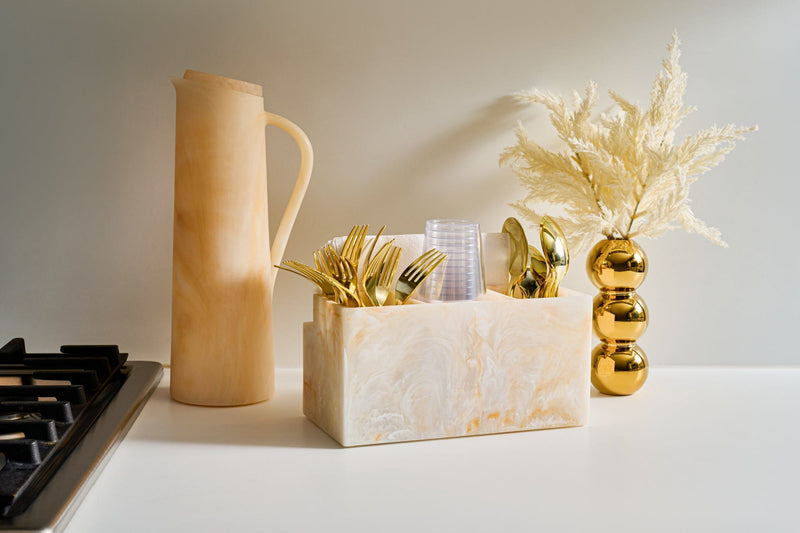 Elegant marble-look utensil holder with gold disposable cutlery and cups, paired with a matching pitcher and styled on a modern kitchen countertop with decorative vase. | Waterdale Collection