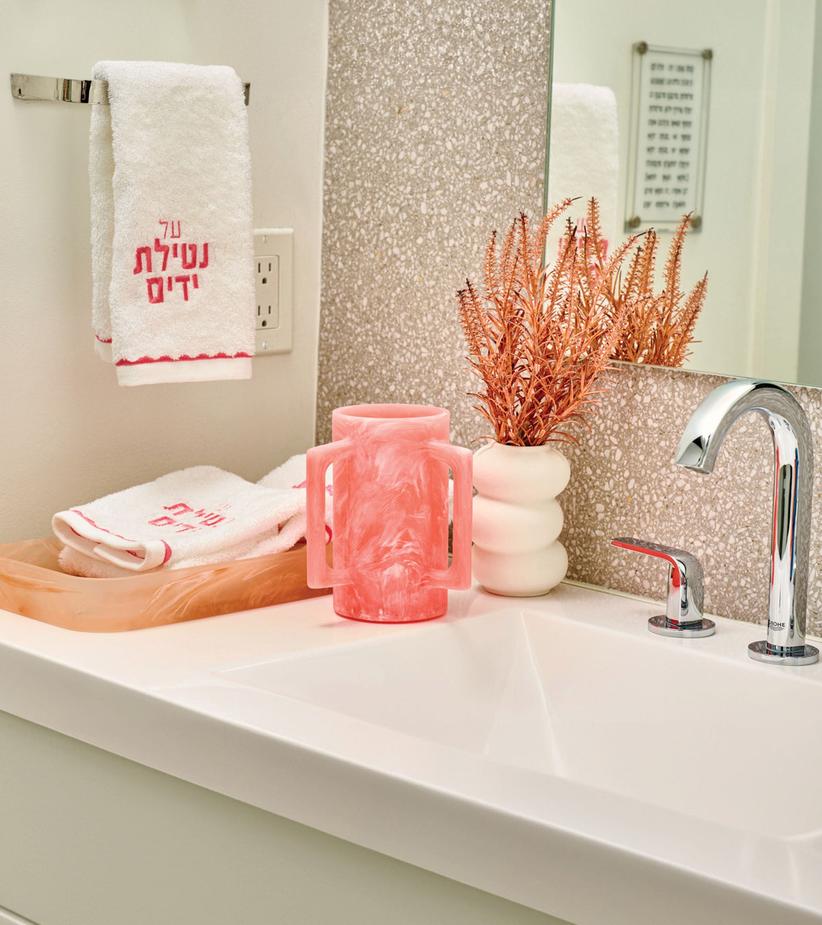 Pink marble-style netilat yadayim washing cup with matching tray and embroidered hand towels, styled on a modern bathroom sink with decorative accents. | Waterdale Collection