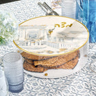 Painted Bais Hamikdash matzah box with wooden base and lucite lid featuring Jerusalem Temple design, displayed with water glass on patterned surface