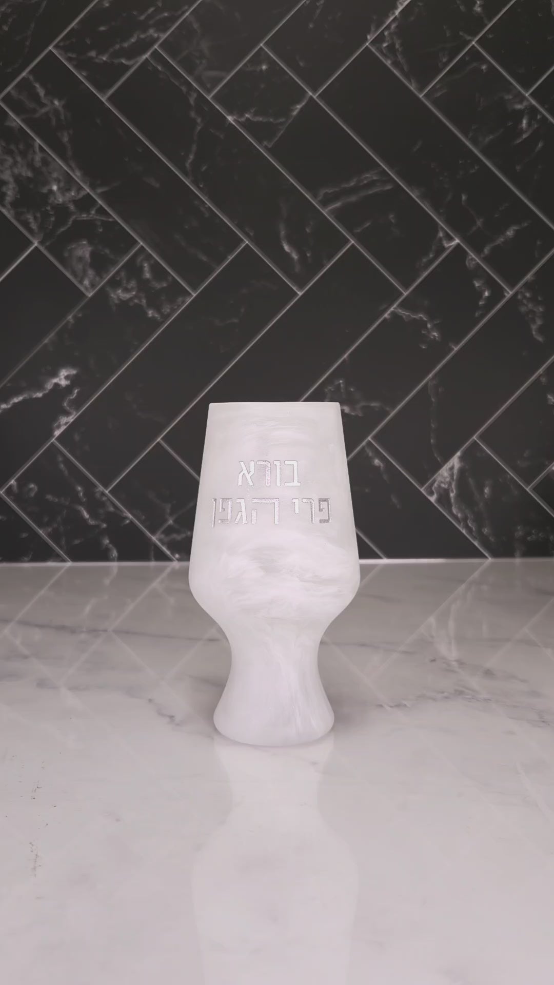 Resin style havdalah cup with words Borei Pri Hagafen on a Havdalah display. Cup being filled up with wine.