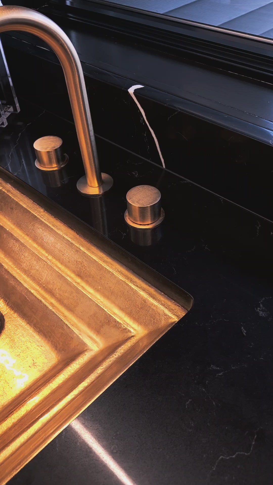 Ombre resin washing cup with gold “Al Netilas Yadayim” Hebrew lettering, displayed beside a white embroidered hand towel on a sleek black marble countertop near a modern sink.