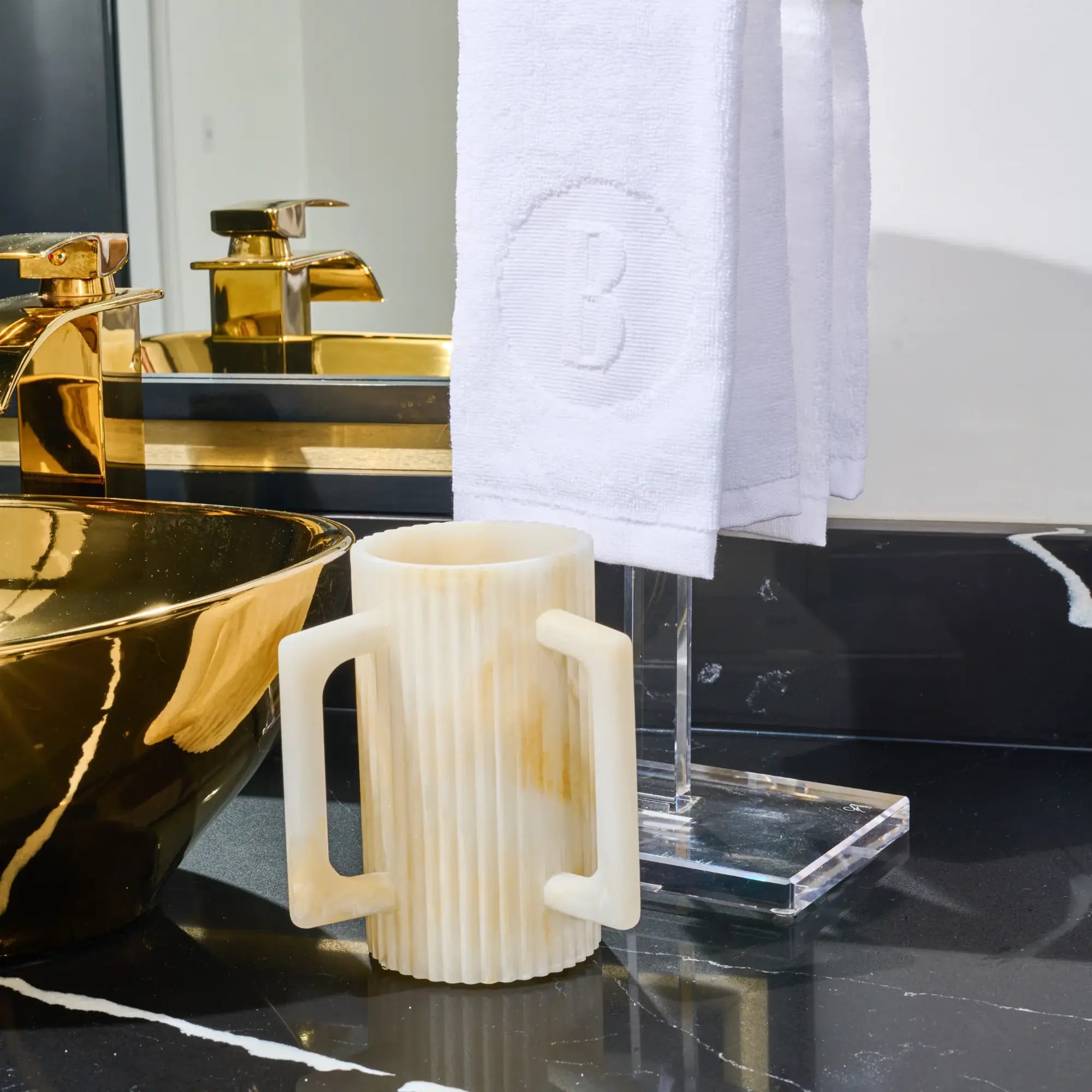 Fluted resin washing cup with two handles for Netilat Yadayim on bathroom counter.