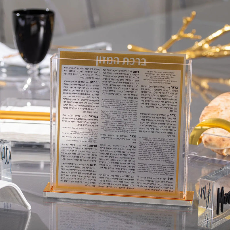 Black & Gold Tablescape by Waterdale Collection featuring elegant gold-framed text card with black glass and decorative gold branches on white table.