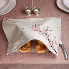 Cherry Blossom Challah Board and Cover Set displayed with fresh challah bread on a mauve tablecloth, featuring delicate pink floral design and linen cover.