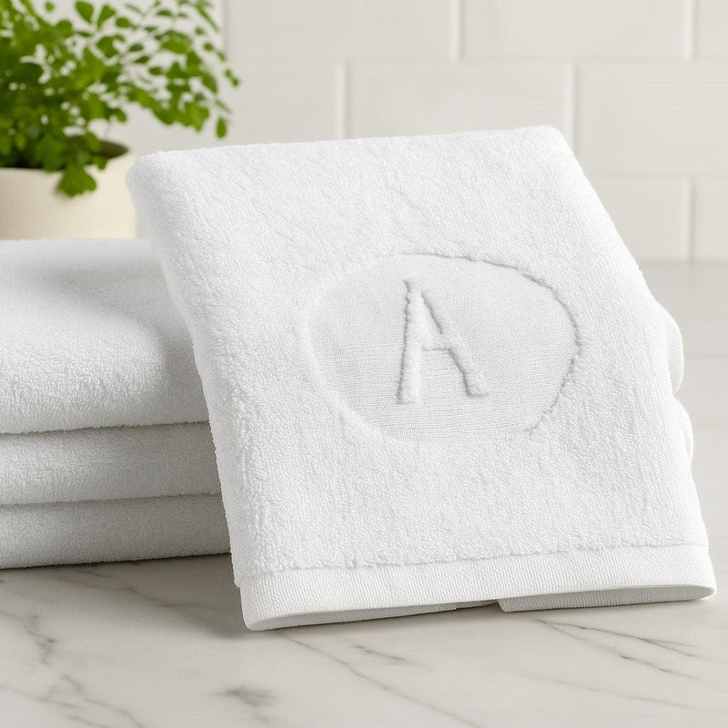 Circle Initial Embossed Cotton Finger Towel on a marble tabletop | Waterdale Collection