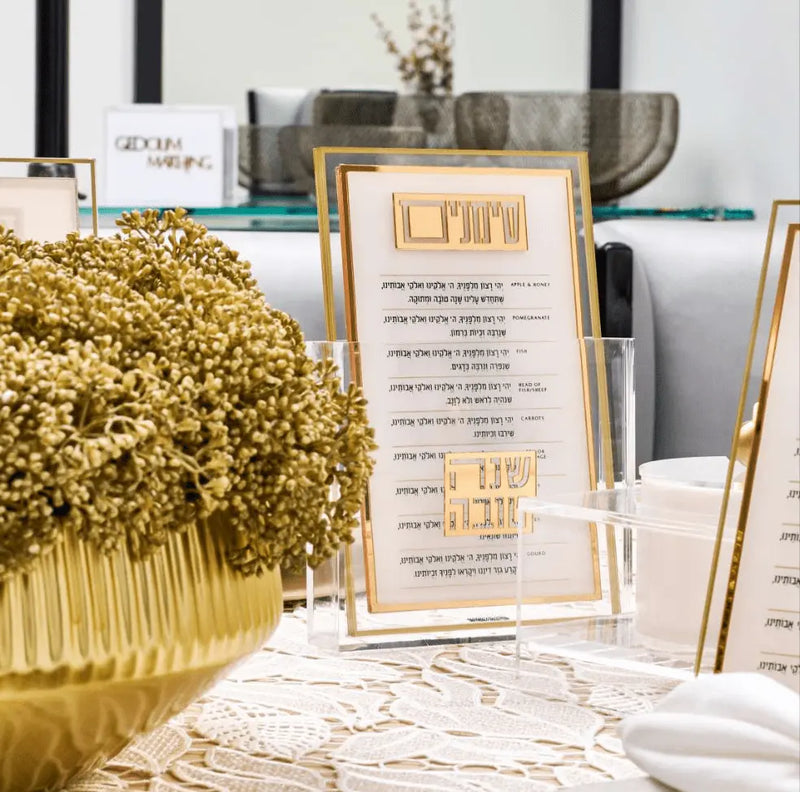 Clear Lucite simanim cards with gold text, styled for a Rosh Hashana tablescape