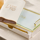 Classic challah board with built-in drawer, featuring a frosted glass cutting surface with gold “Shabbat” detail, gold-tone handles, and a cream “Shabbat Kodesh” challah cover partially draped over the board.