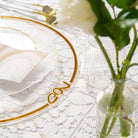 Elegant table setting with gold-rimmed chargers, white napkin, and a vase with greenery on a textured tablecloth.