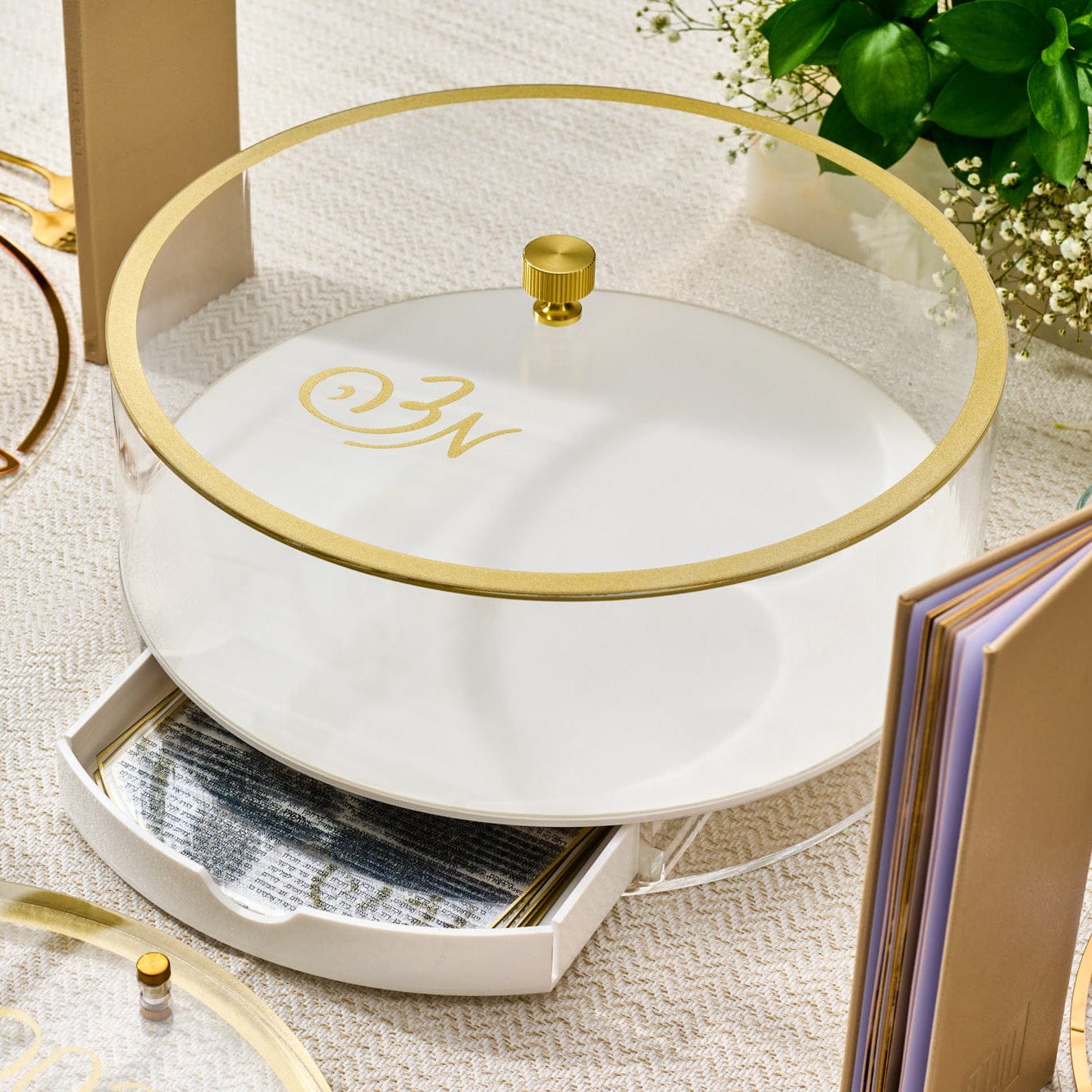 Classic Script bencher set matzah box in white and clear acrylic with gold trim and monogram detail, featuring a matching lid and built-in drawer for benchers, styled on an elegant Passover
