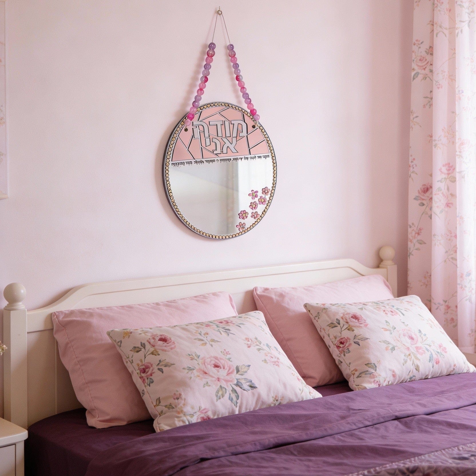 Bedroom with pink walls, floral pillows, and a decorative Color it Acrylic modah Ani mirror - Waterdale Collection