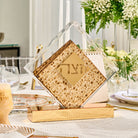 Modern clear acrylic diamond matzah box with a gold mirrored base on a set Pesach Seder table