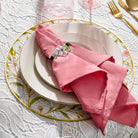 Pink and green lucite floral napkin wrap around a pink napkin set on a plate and floral bird charger.