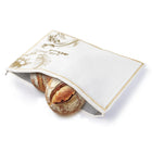 White and gold French Toile Challah Pouch with leather trim, containing a braided challah loaf inside, perfect for Shabbat table.