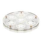 Transparent geometric Seder plate with white concentric circles, brass accents, and two matching matzah compartments by Waterdale Collection.