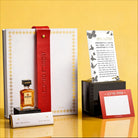 Luxury Mishloach Manot gift box featuring a Onyx Butterfly Hadlokas Neiros in a lucite stand, a white leatherette pouch with a red strap, and a mini Disaronno liqueur.