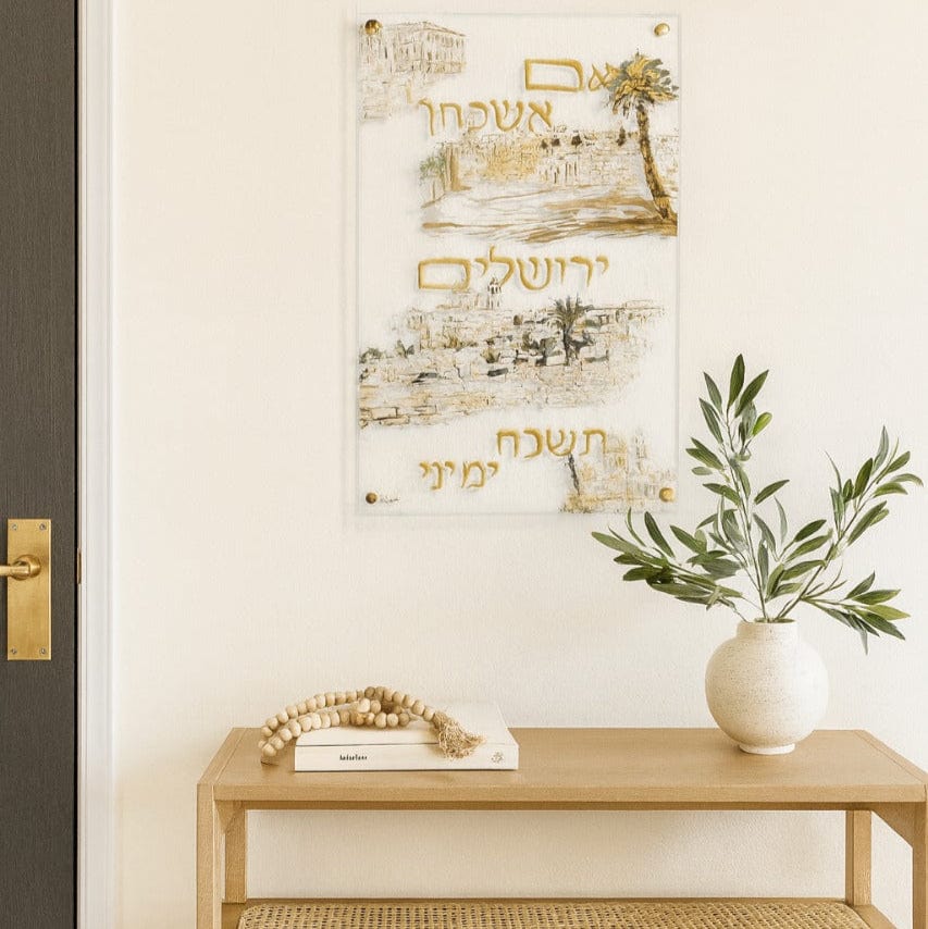 Hand-Painted  Im Eshkachech displayed above a wooden console table with a vase and a decorative bead garland.