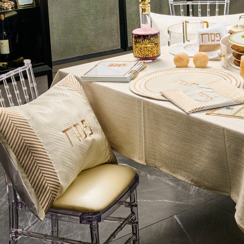 Herringbone Pesach set in cream with gold accents, including matzah cover, afikoman bag, Seder plate, and decorative pillow displayed on an elegant Seder table.