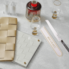 Inspired gold and white printed knife blade cover resting next to a silver-bladed challah knife, displayed on a textured white tablecloth for a Shabbat table setting - Waterdale Collection