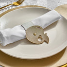 Gold Leather Simanim Napkin Wrap on top of a white plate and Gold leather charger
