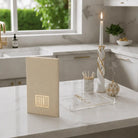 Tan leather Havdalah booklet displayed on white desk with notebook and candle holder in modern home setting.
