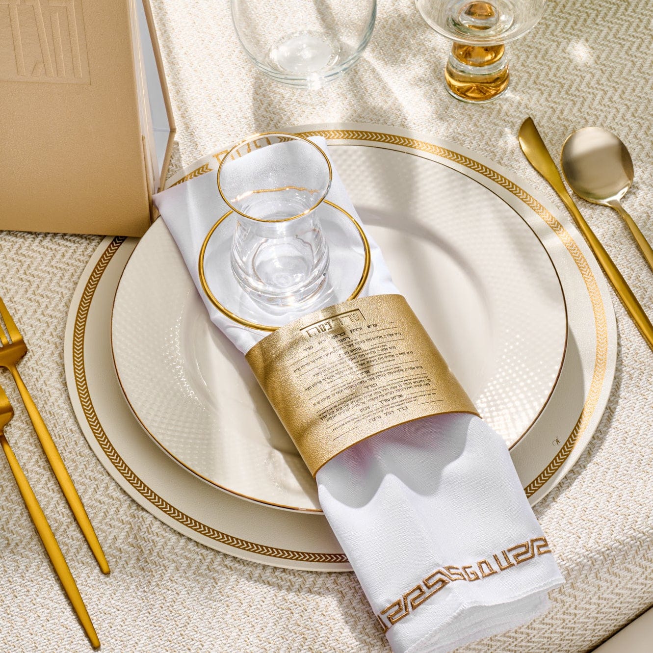 Leather herringbone round charger in cream with gold trim, styled on an elegant table setting with white napkin, gold napkin ring, and glassware.