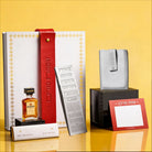 Luxury Mishloach Manot gift box featuring a silver-embossed Shabbat card set, a matching silver leatherette pouch, a mini Disaronno liqueur, and dark chocolate.