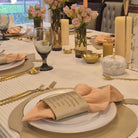 An elevated shot of a table setting featuring a Gold Leather Simanim Napkin Wrap on a white plate, leather gold apple charger and cutlery on Rosh Hashanah Tablescape
