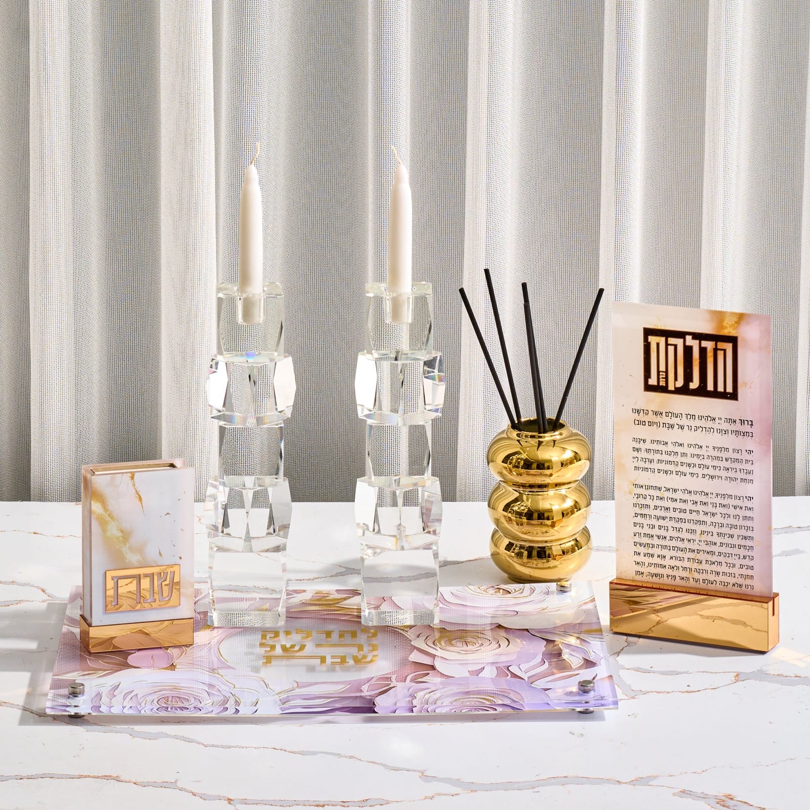 Decorative items including candles, a diffuser, and a card on a marble surface with a curtain background.