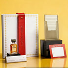Luxury Mishloach Manot gift box featuring a white leatherette Havdalah pouch with a grey leather fastener, Disaronno liqueur, and gourmet dark chocolate.