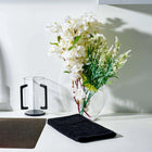 Modern Netilas Yadayim set by Waterdale featuring white pitcher and black base with fresh flowers in clear vase