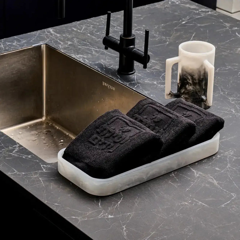 Ombre resin washing cup in black and cream gradient displayed on marble countertop next to sink, styled with bathroom accessories