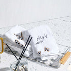Onyx Butterfly Towel Set by Waterdale Collection displayed on white marble surface with brushes and design sketches nearby.
