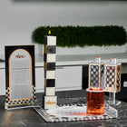 Onyx Havdalah set with black and white striped candle holder, spice container, and kiddush cup arranged on a decorative tray with greenery backdrop.
