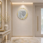 A round decorative wall art piece with gold and white marbled accents and black Hebrew text, mounted on a beige wall in a modern, elegant hallway with a console table and vase.