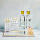 Painted by Judy Hadlokas Neiros Set displayed with decorative candles, instruction cards, and brass holders on white surface
