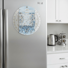 Painted Kosel Calendar Wheel magnet mounted on a stainless steel refrigerator in a modern kitche, featuring a blue Western Wall painting and Hebrew monthly names on the rotating wheel - Waterdale Collection