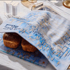 Painted Yosefa challah board and cover set with blue watercolor design, displayed with fresh challah bread and wine on white table.