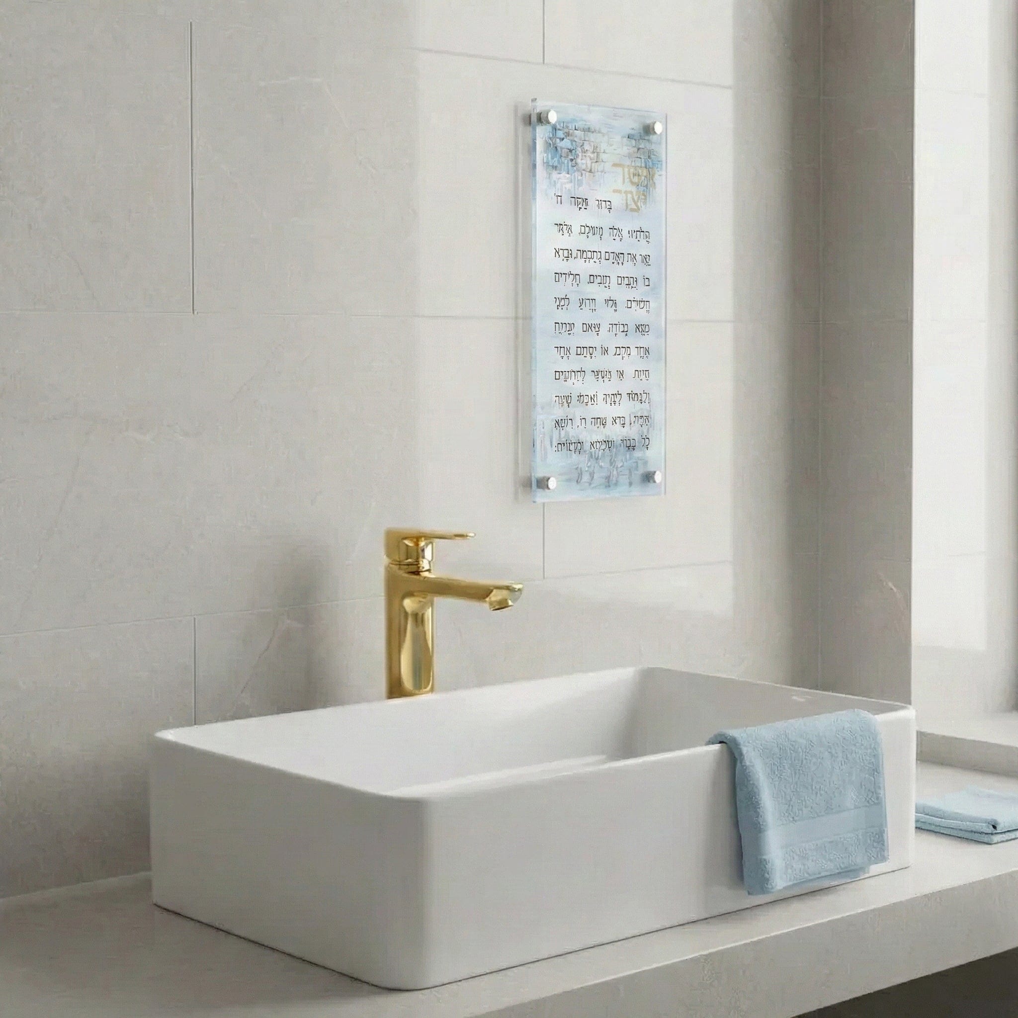 Painted Yosefa Kosel Asher Yatzar featuring elegant Hebrew text set against a serene blue-toned Kosel artwork with subtle gold accents, mounted in a sleek lucite wall frame on a modern bathroom.