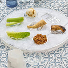 Pearlstone Seder plate with pearl marble finish displaying traditional Passover foods in compartments, set on decorative blue and white tablecloth for holiday table.
