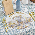 Pesach Bais Hamikdash charger with Jerusalem illustration and gold Hebrew lettering displayed on a blue patterned Seder table with gold flatware and glassware.