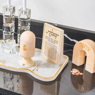 Cream resin arch tzedakah box with Hebrew text, displayed on a resin base with candlesticks and resin match cloche and resin brachos block