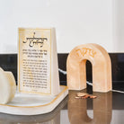 Cream resin arch tzedakah box with Hebrew text, displayed near  a resin base with resin brachos block