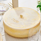 Cream-colored resin matzah box with lid and gold accents, displayed on a table setting for Passover.