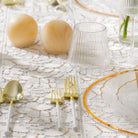 Table setting with Resin gold salt shakers and gold and clear glassware on a textured tablecloth - Waterdale Collection