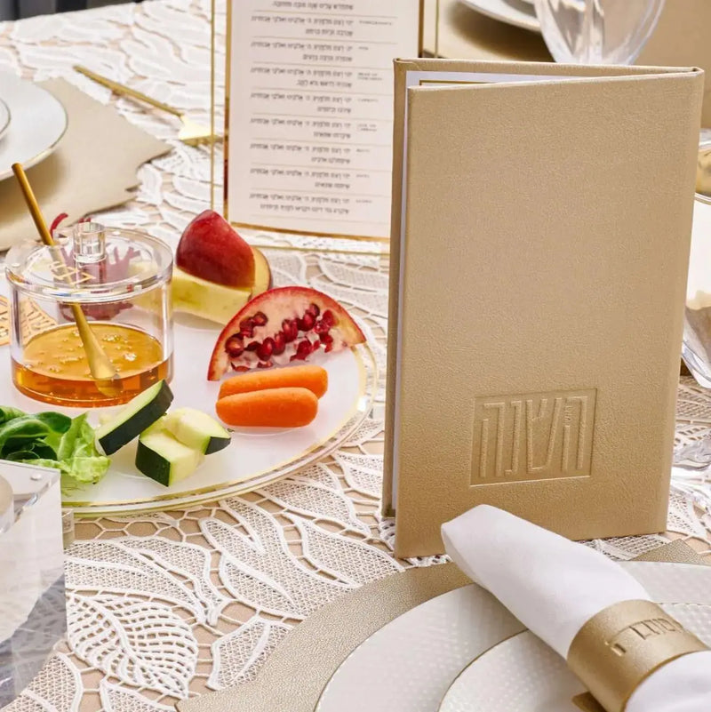 Rosh Hashanah Classic 2.0 tablescape featuring gold-trimmed plates, pomegranate cocktails, menu cards, and elegant place settings on white linens.