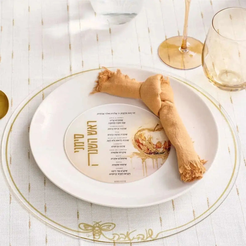 Rosh Hashanah rustic tablescape with painted plate, honey dipper, and gold accents on white linen table setting.