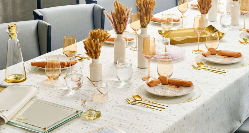 Rosh Hashanah 2024 rustic tablescape with white linens, gold wheat stems, place settings, and neutral décor on dining table
